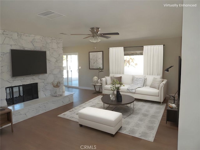 living room featuring hardwood / wood-style flooring, a stone fireplace, and ceiling fan