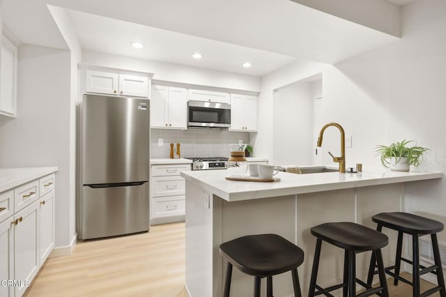 kitchen with backsplash, a breakfast bar, sink, white cabinetry, and stainless steel appliances