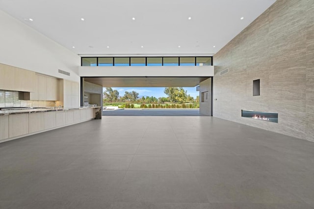 interior space featuring a large fireplace, a high ceiling, and concrete floors