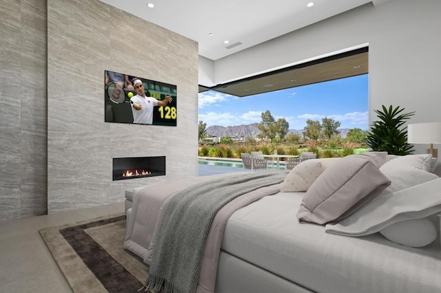 bedroom with a tiled fireplace, concrete floors, and multiple windows