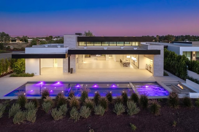 back house at dusk featuring an outdoor fire pit and a patio area