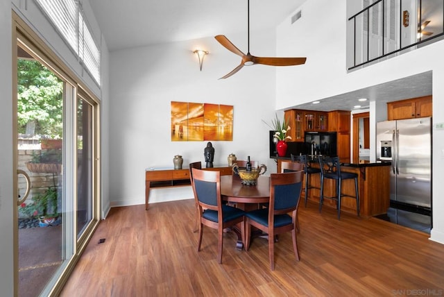 dining space with hardwood / wood-style flooring, a high ceiling, and ceiling fan