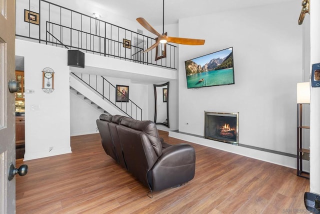 living room with a high ceiling, ceiling fan, and hardwood / wood-style floors