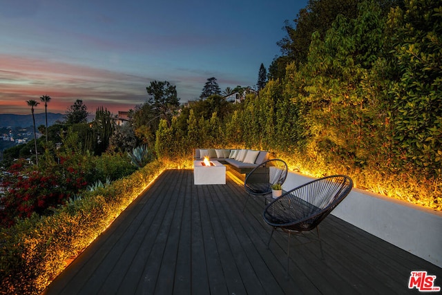 deck at dusk featuring an outdoor living space with a fire pit