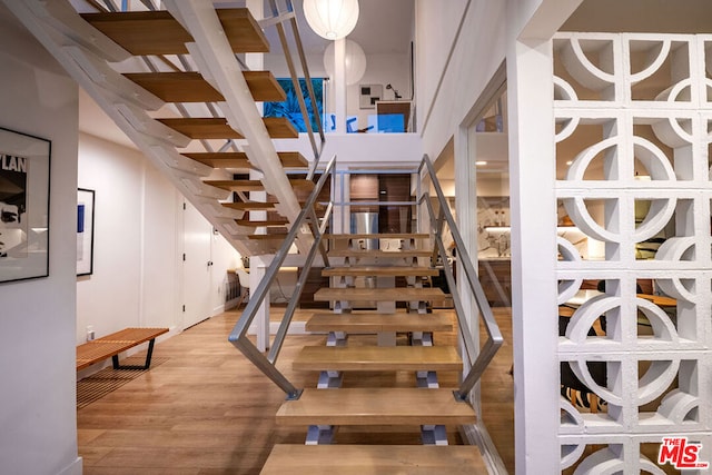 stairs with wood-type flooring and a high ceiling