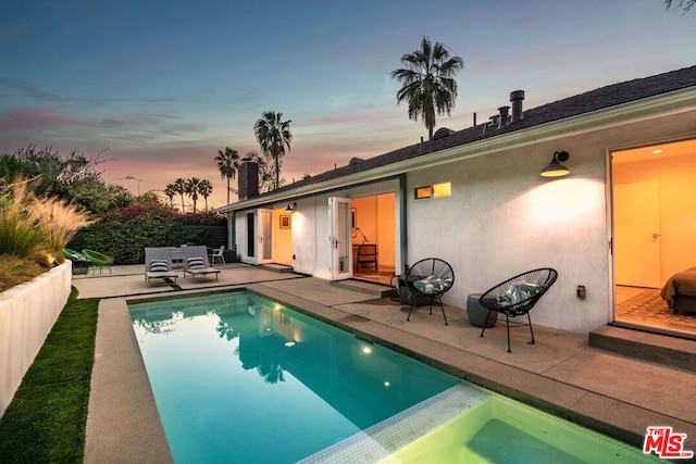 pool at dusk featuring a patio