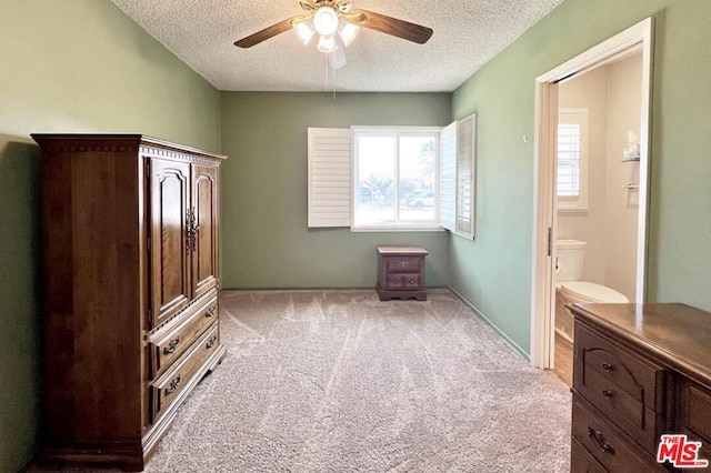 unfurnished bedroom with light carpet, ceiling fan, a textured ceiling, and connected bathroom