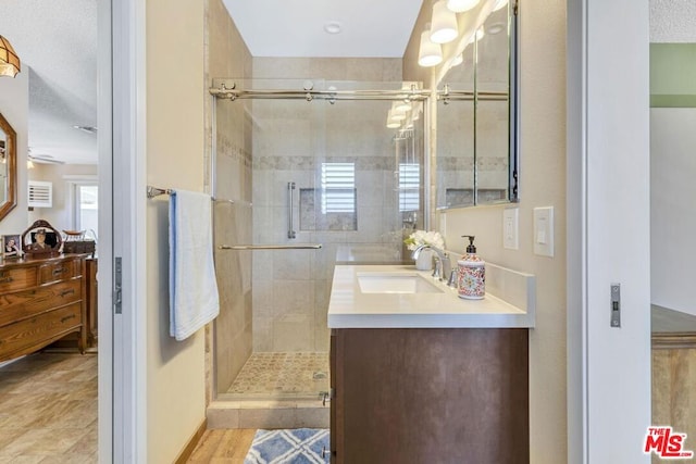 bathroom with a textured ceiling, a shower with door, wood-type flooring, and vanity