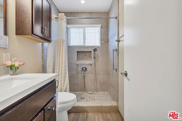 bathroom with hardwood / wood-style floors, toilet, walk in shower, and vanity