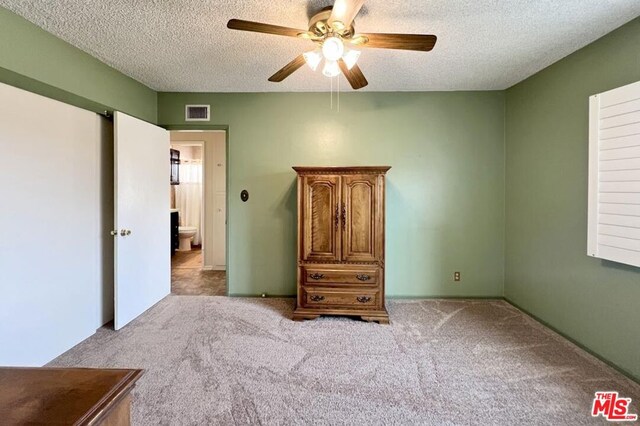 unfurnished bedroom featuring ceiling fan, light colored carpet, and a textured ceiling