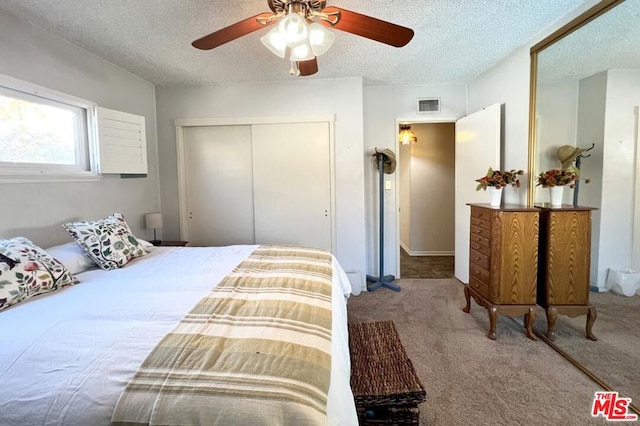 bedroom featuring a textured ceiling, ceiling fan, a closet, and carpet floors