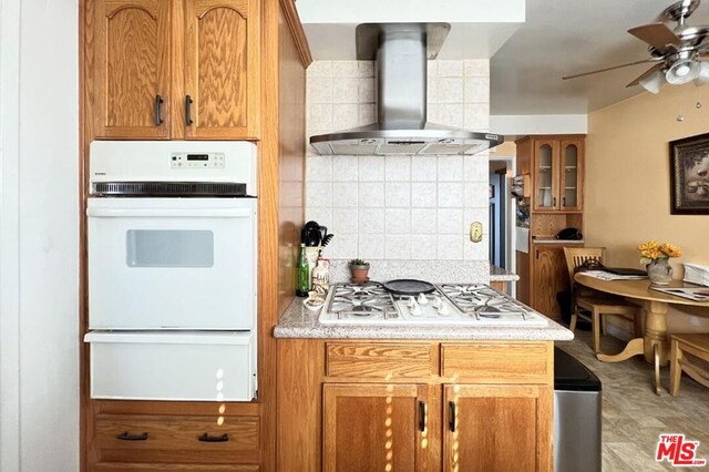 kitchen with white appliances, ceiling fan, tasteful backsplash, and wall chimney range hood