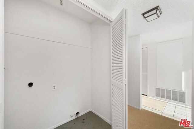 clothes washing area with carpet, hookup for an electric dryer, gas dryer hookup, and a textured ceiling