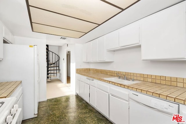 kitchen with sink, white cabinetry, tile countertops, and white appliances