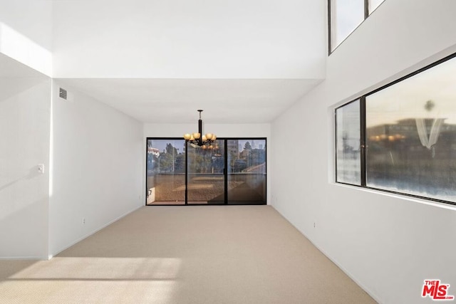 empty room with light carpet and a notable chandelier