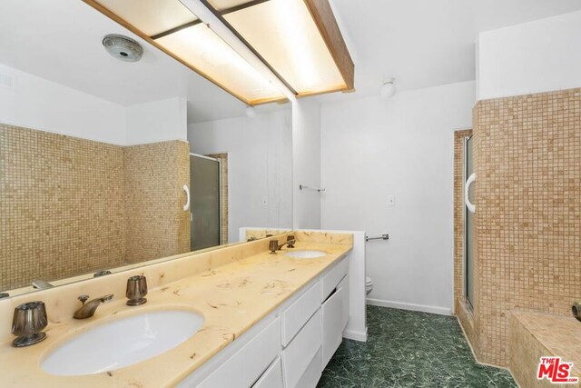 bathroom featuring a shower with shower door, vanity, and toilet