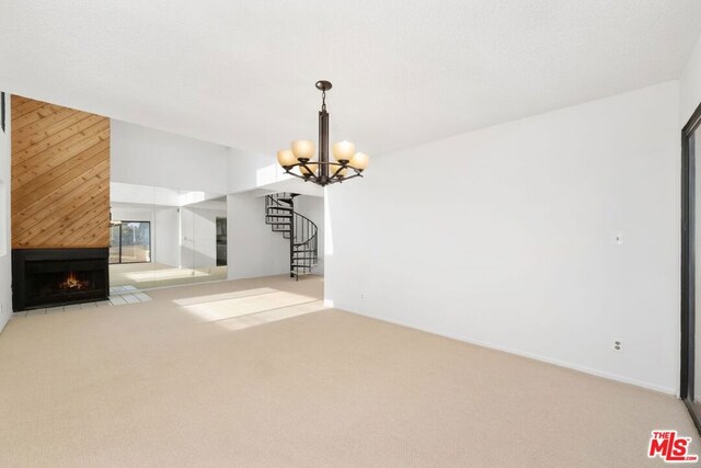 unfurnished living room featuring a fireplace, light carpet, and an inviting chandelier