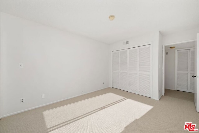 unfurnished bedroom with a closet and light colored carpet