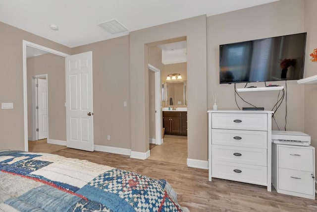 bedroom featuring light wood-type flooring and connected bathroom