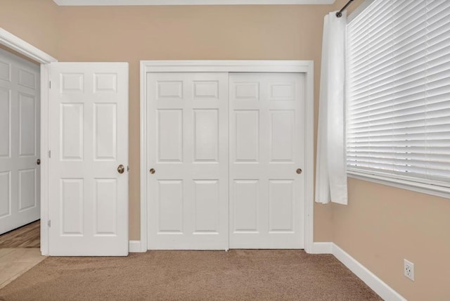 unfurnished bedroom featuring light carpet and a closet