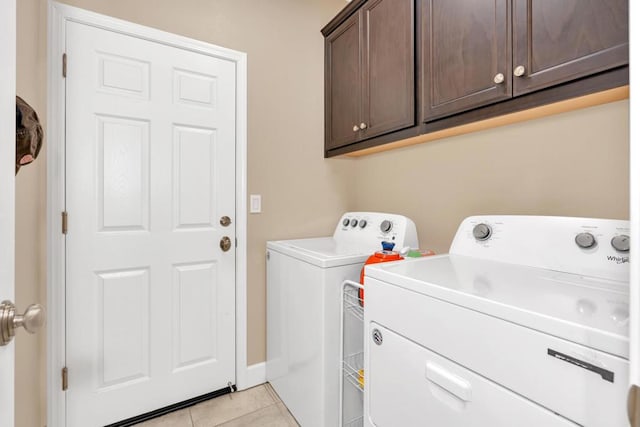 laundry room featuring cabinets, light tile patterned floors, and washing machine and dryer