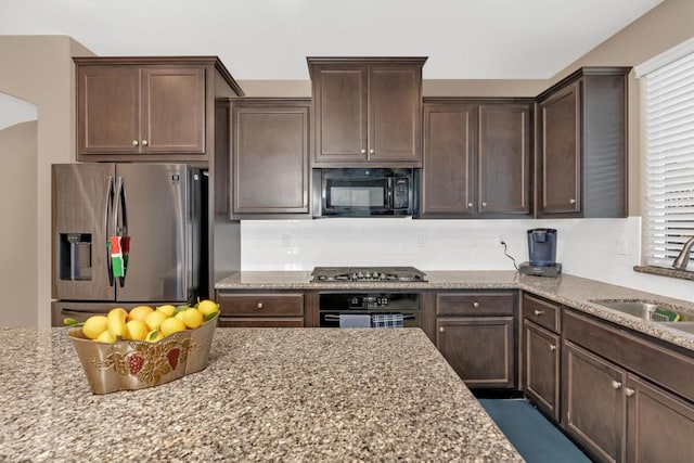 kitchen featuring light stone countertops, black appliances, and sink