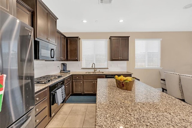 kitchen featuring light tile patterned floors, light stone countertops, stainless steel appliances, and sink