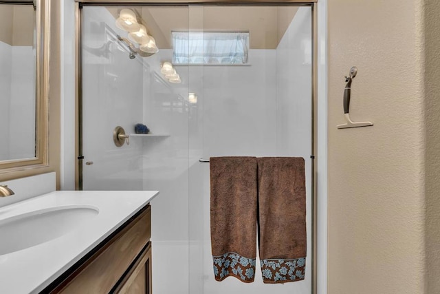 bathroom featuring a shower with shower door and vanity