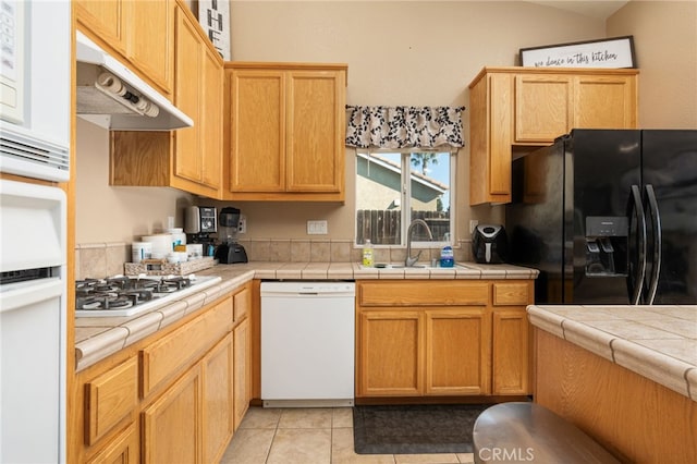 kitchen featuring black refrigerator with ice dispenser, sink, tile countertops, light tile patterned flooring, and white dishwasher