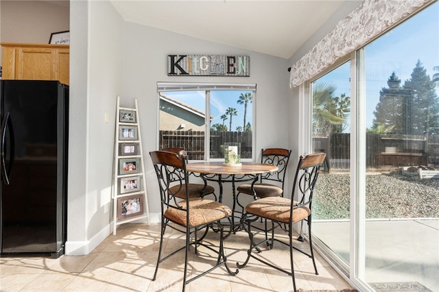 dining room featuring vaulted ceiling, light tile patterned floors, and plenty of natural light