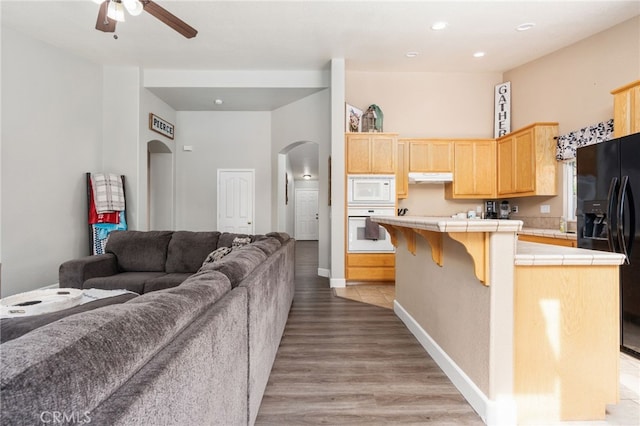 kitchen with tile countertops, a center island, white appliances, light hardwood / wood-style flooring, and light brown cabinetry