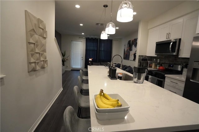 kitchen with stainless steel appliances, tasteful backsplash, decorative light fixtures, white cabinets, and sink