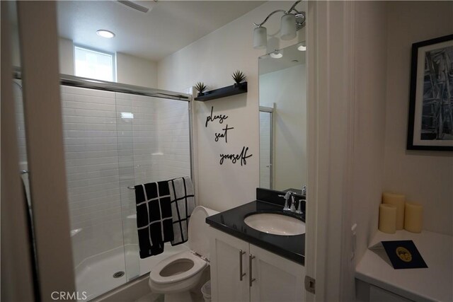 bathroom featuring toilet, vanity, and walk in shower