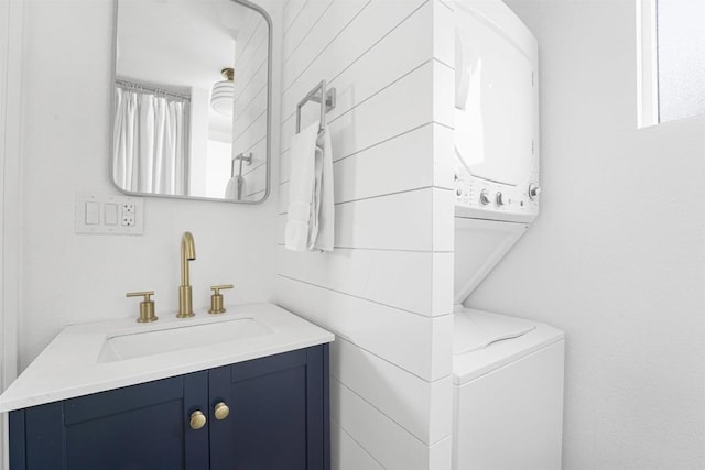 bathroom featuring stacked washer / drying machine, vanity, and toilet