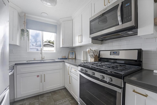 kitchen with tasteful backsplash, white cabinets, appliances with stainless steel finishes, and sink