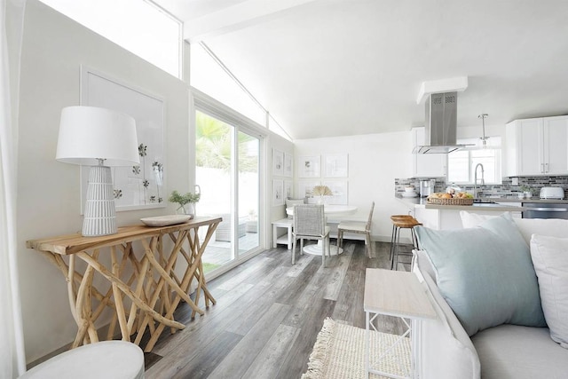 interior space with white cabinetry, ventilation hood, decorative backsplash, vaulted ceiling with beams, and sink