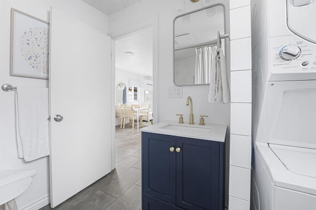 bathroom featuring stacked washer / dryer, tile patterned flooring, and vanity