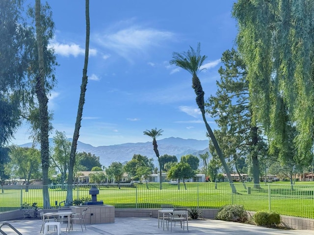 surrounding community with a mountain view, a lawn, and a patio area