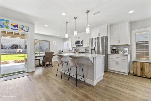 kitchen with decorative light fixtures, light hardwood / wood-style floors, white cabinetry, and stainless steel appliances