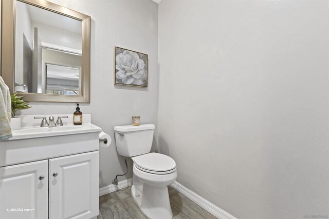 bathroom with toilet, hardwood / wood-style flooring, and vanity