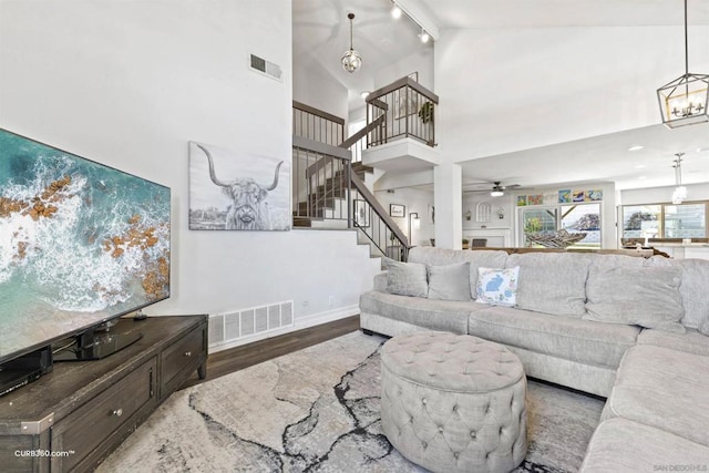 living room with high vaulted ceiling, ceiling fan with notable chandelier, and hardwood / wood-style floors