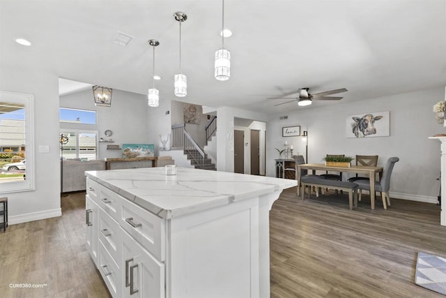 kitchen featuring decorative light fixtures, ceiling fan, a kitchen island, wood-type flooring, and white cabinetry