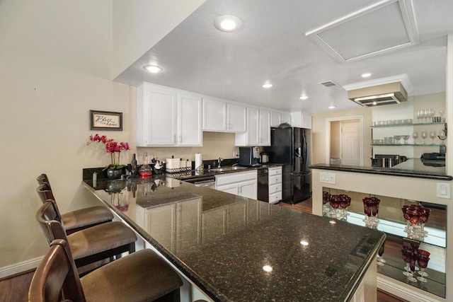 kitchen with white cabinets, black refrigerator with ice dispenser, dark hardwood / wood-style flooring, a kitchen breakfast bar, and kitchen peninsula