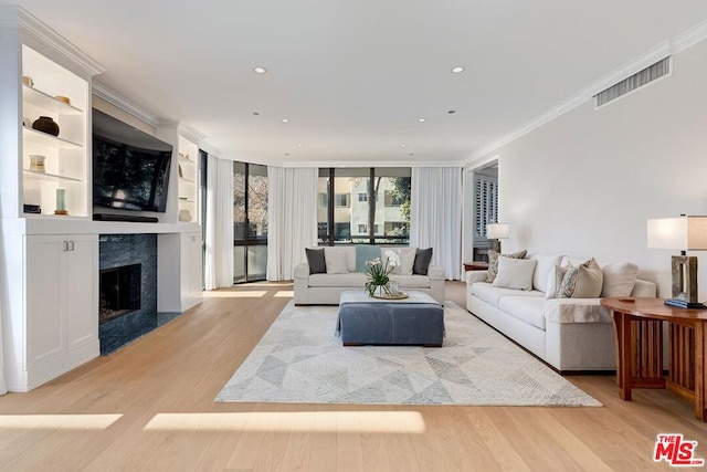 living room featuring light wood-type flooring, a premium fireplace, ornamental molding, and floor to ceiling windows