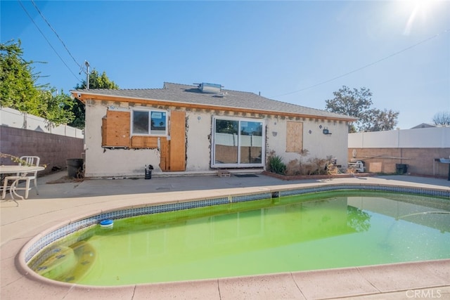 rear view of house with a fenced in pool and a patio