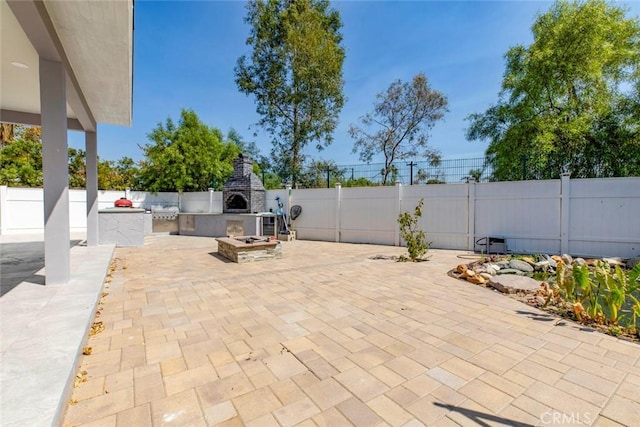 view of patio featuring exterior kitchen and an outdoor stone fireplace