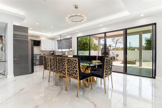 dining space with sink, a tray ceiling, and a chandelier