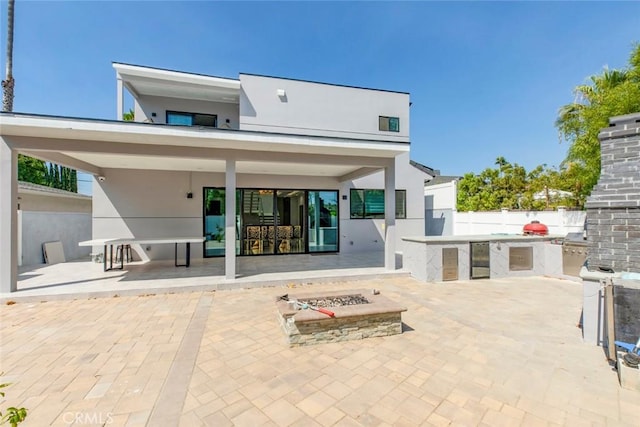 rear view of property with an outdoor fire pit, exterior kitchen, and a patio area