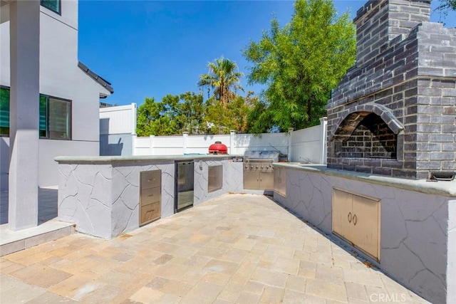 view of patio with grilling area, an outdoor kitchen, and exterior fireplace