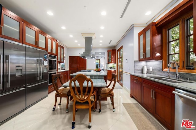 kitchen featuring light stone countertops, stainless steel appliances, sink, island range hood, and crown molding